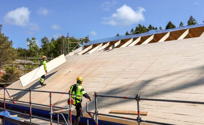 Arbetare med gul väst jobbar på hustak