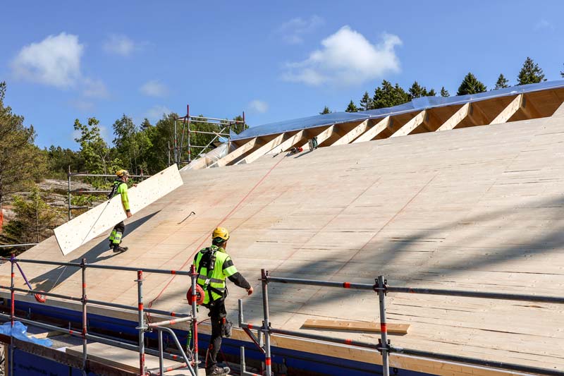 Arbetare med gul väst jobbar på hustak